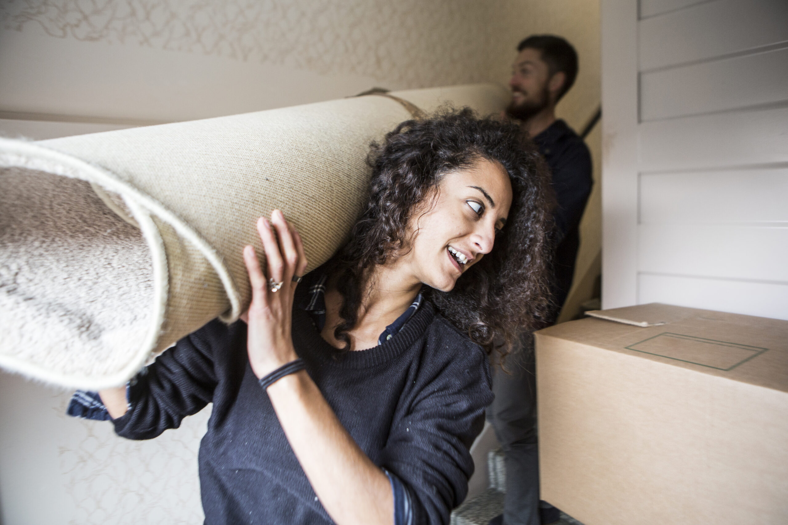 Woman and man carrying carpet while moving house