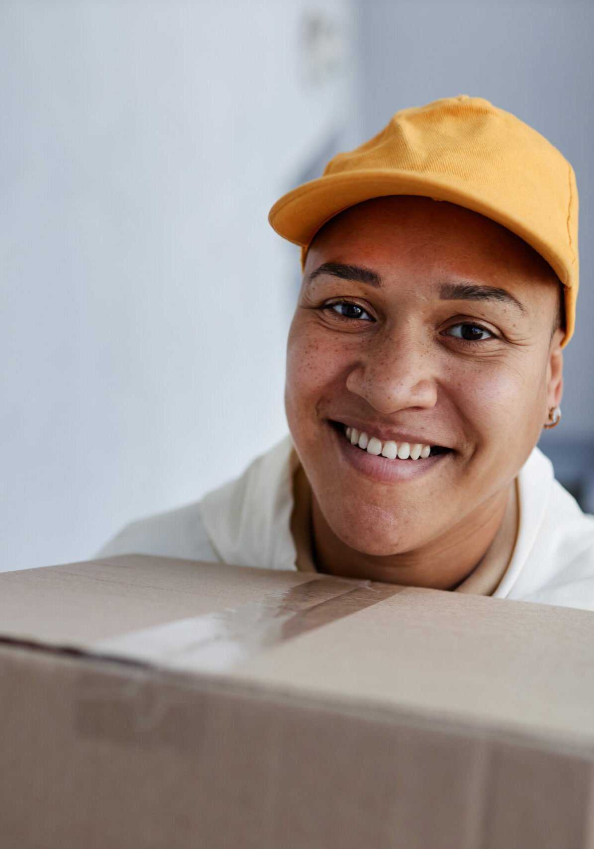 Portrait of smiling delivery worker going up stairs to house door with package, copy space